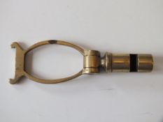 A brass 12-bore combination whistle and cartridge extractor, stamped 12.