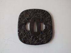 A large square form blackened iron tsuba, profusely decorated to either side with waves.