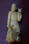 A Japanese carved ivory figure of a fisherman, holding a trident, a basket of fish at his feet, 10cm