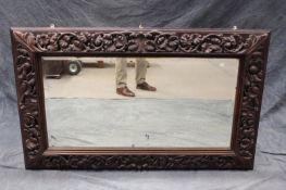 A large 19th Century carved oak framed mirror, with relief decoration of vines and leaves, 148 x