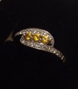 A white metal Ring featuring small Yellow Sapphires and two bands of White Sapphires in crossover