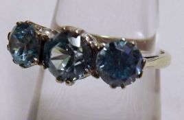 A yellow metal three Light Blue Stone Dress Ring