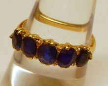 An unmarked yellow metal five graduated Mid-Blue Sapphire Ring, claw set