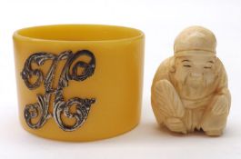 A small Oriental Ivory Netsuke carved in the form of a seated figure with palm leaf in his right
