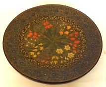 A Circular Lacquered Papier-mâché Wall Plaque, decorated with panels of foliage in colours, 17”