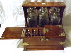 A late 19th/early 20th Century Oak Tantalus, mirror back and fitted with three lead crystal