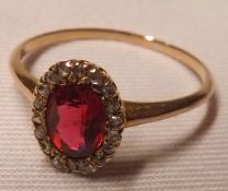 An unmarked yellow metal centre oval Pale Red Stone and small Diamond surround Cluster Ring