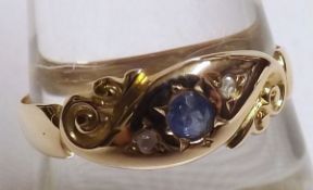 A late Victorian hallmarked 15ct Gold Ring, the carved front featuring a small Mid-Blue Sapphire and