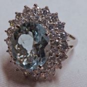 A white metal large Cluster Ring, featuring a central oval Aquamarine surrounded by two bands of