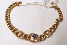 An unmarked Victorian Gold curb link Bracelet featuring a Mid-Blue Sapphire and two Seed Pearls to