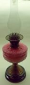 A late 19th Century Oil Lamp with pink opaque glass font, a stepped round brass foot, raised on a