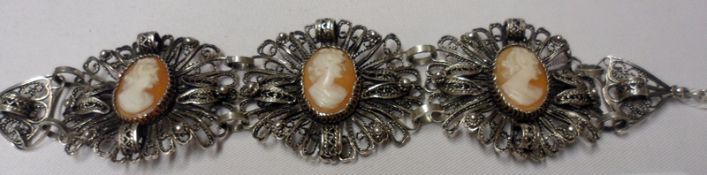 A Foreign white metal Filigree Panelled Bracelet featuring three Shell Cameos of ladies heads,