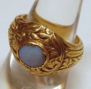 A precious metal Antique Gold Ring with carved detail and featuring an oval Moonstone to the centre