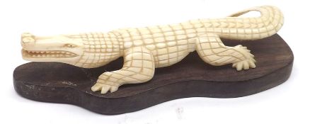 An early 20th Century Carved Bone or Ivory Model of a crocodile standing on an integral hardwood