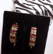 A pair of mid-grade yellow curve design Earrings, pavé set with approximately 1 ct of Rubies and .36