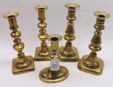 A collection of five Brass Candlesticks, on typical knopped columns, raised on square bases,