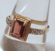 A yellow metal Centre Emerald Cut Garnet and two small Diamond Ring, stamped “10K”