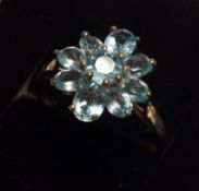 A white metal nine Blue Apatite set Dressing Ring of flower head design with small Diamond chips