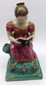 A large 19th Century Staffordshire Figure of a reading girl in seated position, raised on a square