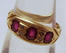 An early 20th Century 18ct Gold Ring set with three Red Stones and four small Old Cut Diamonds (