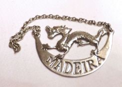 A Chinese white metal Decanter Label, modelled as a dragon over a crescent, marked “Madeira”,