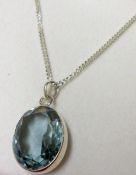 A white metal framed oval cut Aquamarine Pendant on trace chain, stamped “925”, 21mm x 17mm