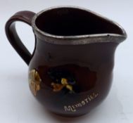 A Doulton Kings Ware Jug, decorated with various figures on a brown background, fitted with a silver