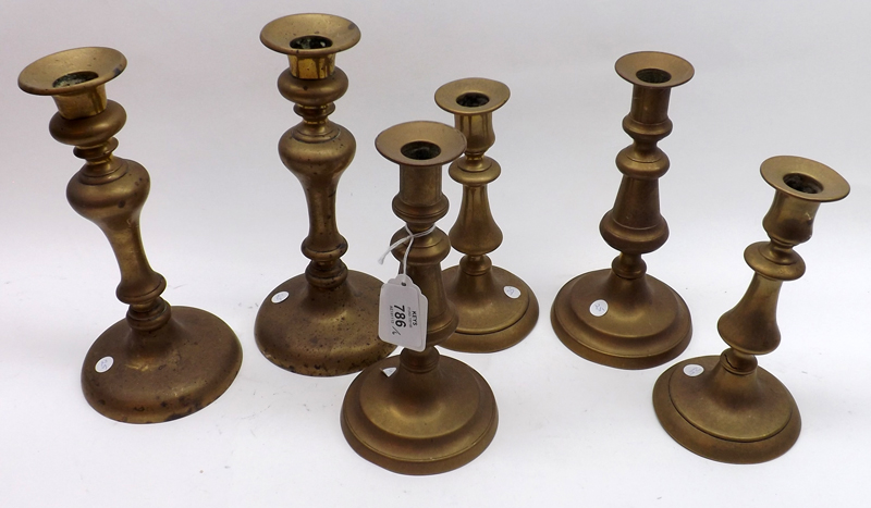 A group of six 19th Century Brass Candlesticks with knopped stems, raised on spreading round
