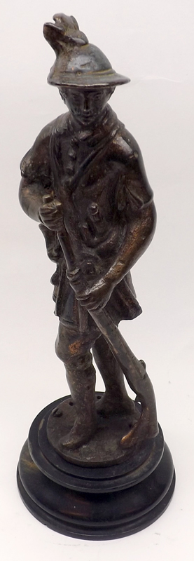 A Bronzed Figure of a Huntsman with gun, raised on a round ebonised base, 11” high