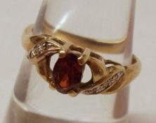 A hallmarked 9ct Gold Red Stone Ring with Diamond chip shoulders, to a pierced setting