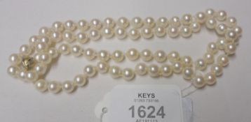 A Single Strand Cultured Pearl Necklace with yellow metal ball clasp, 64cm long, the pearls are