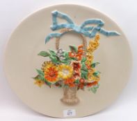 A Clarice Cliff Wall Charger, decorated with a raised design of coloured basket of flowers on a