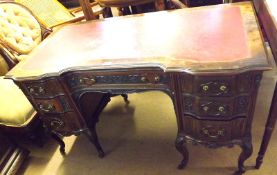 An early 20th Century American Walnut Desk, the top with gilt tooled red inset, the shaped front