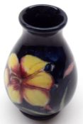 A small Moorcroft Baluster Vase, Freesia pattern, decorated with flowers on a blue background, the