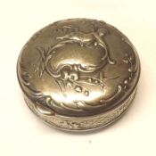 A Continental white metal Round Trinket Box, the hinged lid decorated with a cherub and sprays of
