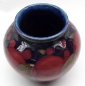 A small Squat Moorcroft Vase, decorated in a pomegranate pattern on a blue background, base with