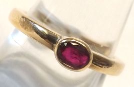 A mid-grade yellow metal Ring set with a red stone