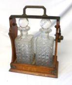 An early 20th Century Oak and Formerly Silver Plated Mounted Two Bottle Tantalus, 10” wide