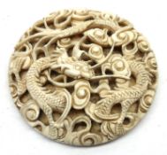 An early 20th Century Oriental Carved Ivory Round Panel, decorated with a pierced design of dragon