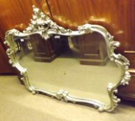 A large 20th Century Wall Mirror in extensively foliate carved silvered frame (glass A/F to one