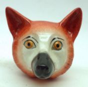 A Staffordshire Stirrup Cup modelled as a fox’s head, decorated in orange and black on a cream