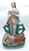 A large 19th Century Staffordshire Figure of a huntsman astride a dead lion, decorated throughout in