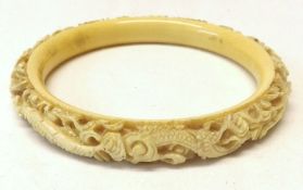 A Circular early 20th Century Carved Ivory or Bone Bangle, decorated with dragons etc, 3 ¾” diameter