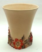 A Clarice Cliff Trumpet Vase, with plain pale puce body and coloured relief moulded floral foot,