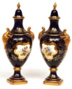 A pair of Coalport Covered Urns with double gilt mask urn handles, decorated with panels of birds