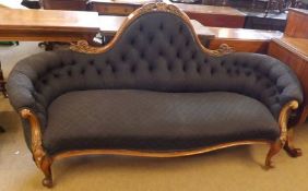 A Victorian Walnut Framed Sofa with arched swept back with carved detail, upholstered in modern dark