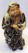 A Chinese Pottery Figure of a hooded man, decorated with streaked ochre and treacle design with