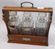 A late 19th Century Oak Tantalus with brass bindings, complete with three square glass spirit