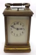 A Lacquered Brass Cased Carriage Clock with swivelling carry handle over bevelled glass panels and