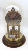 A Brass Anniversary type Revolving Pendulum Timepiece, under a glass dome and raised on a brass